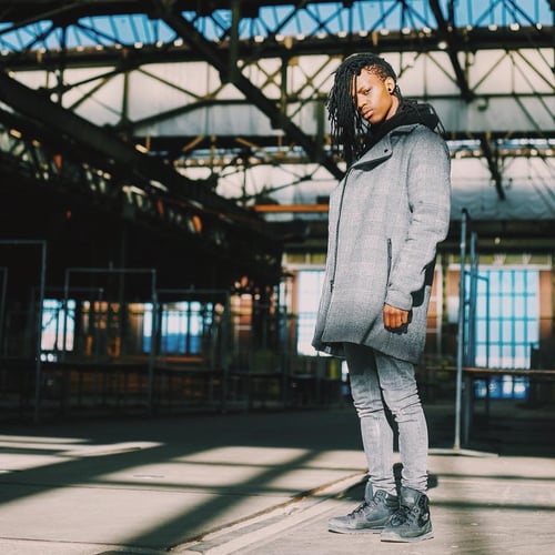 Valentino Kemper in a grey coat in an industrial hall